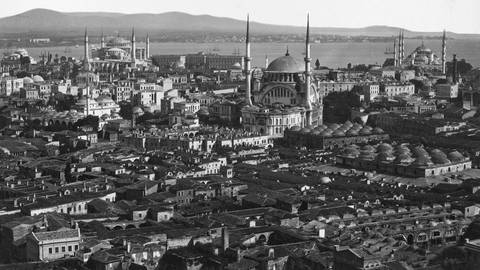 Weiter Blick auf die Stadt Istanbul in schwarz-weiß, im Vordergrund Häuser und Moscheen, im Hintergrund das Meer